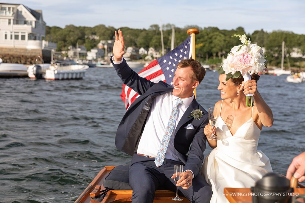 A bride and groom arrive to their wedding reception by boat at Annisquam Yacht Club in Gloucester MA.