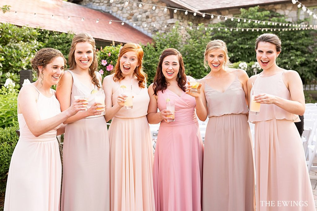 Bridesmaids in soft pink dresses celebrate the wedding in the garden at Willowdale Estate.